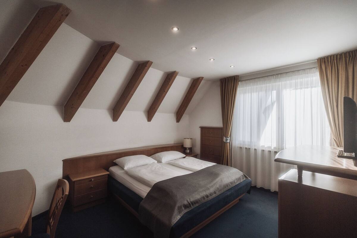 Une chambre d’hôtel comprenant un lit, une table de chevet, une lampe et un bureau avec une chaise.