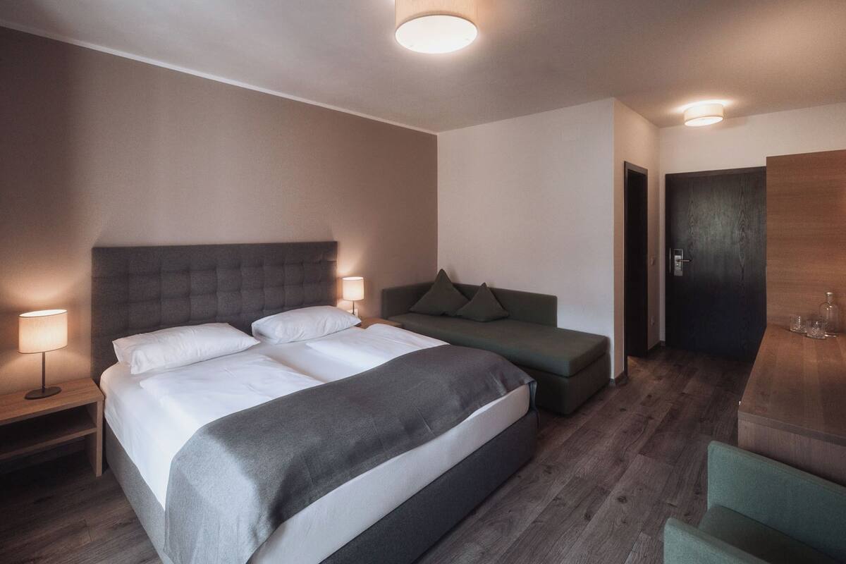 Une chambre d’hôtel moderne avec un grand lit, un canapé, un bureau et une porte.