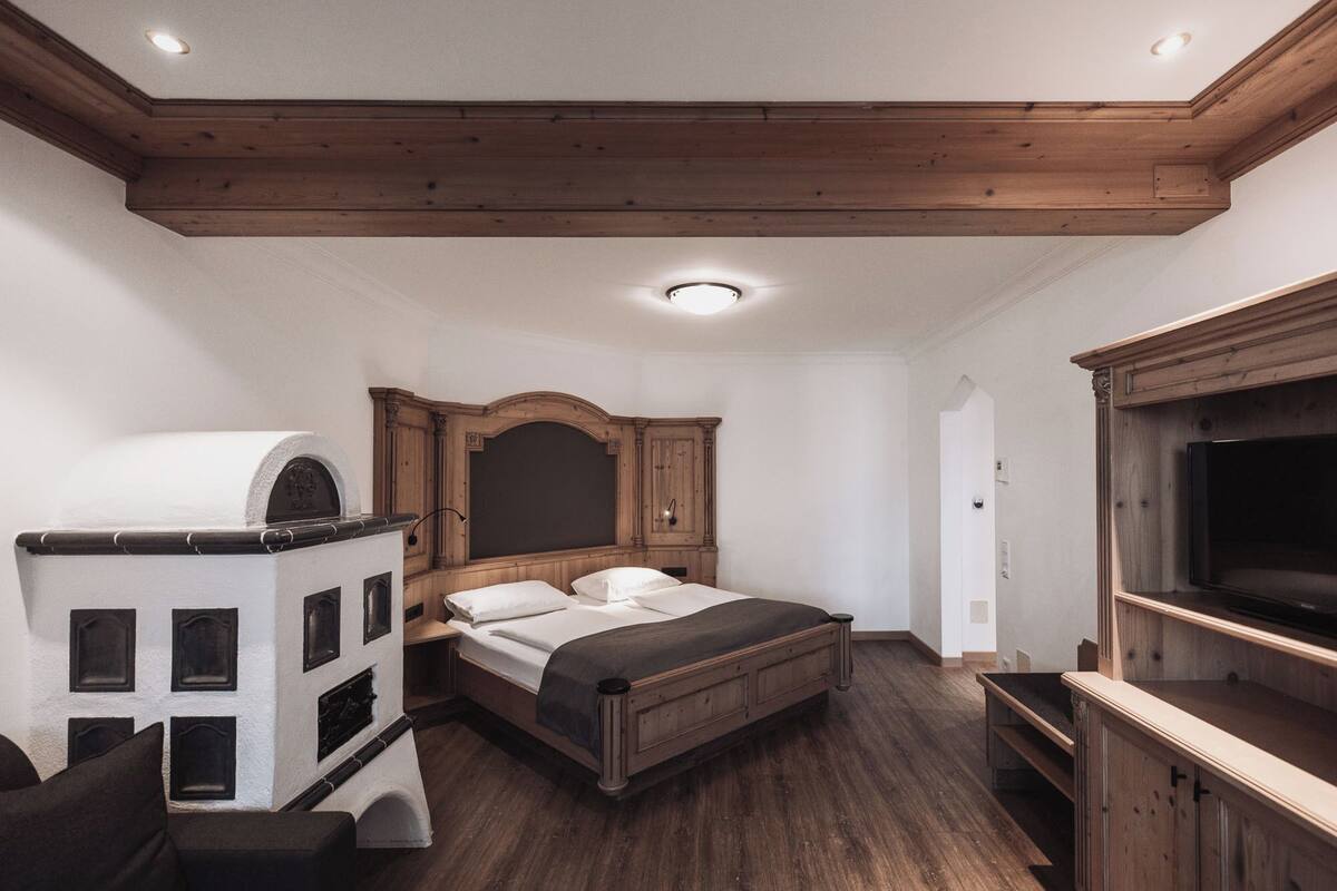 Une chambre à coucher avec un lit en bois, un téléviseur intégré et une cheminée.