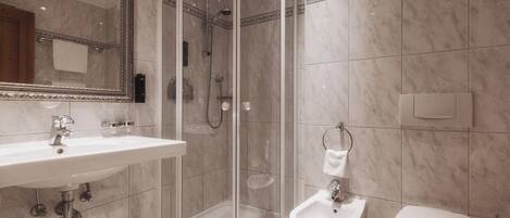 Un baño moderno con ducha envuelta en vidrio, lavamanos e inodoro.
