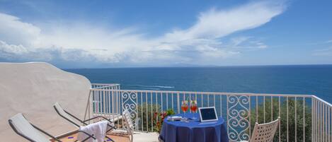 A terrace with a table and chairs, overlooking the sea.