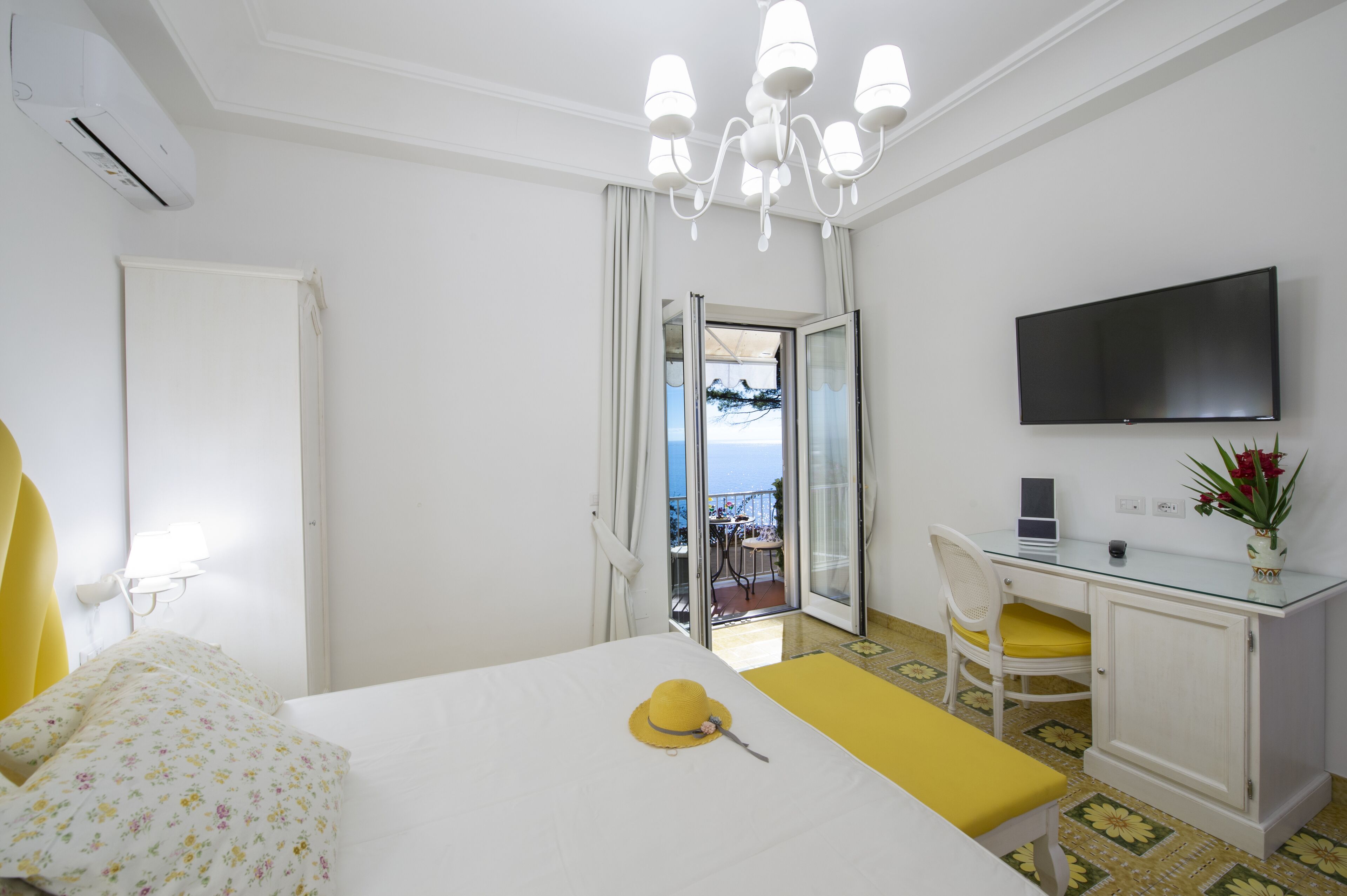 Une chambre d’hôtel avec un lit, un bureau équipé d’un ordinateur, une télévision et un balcon avec vue.