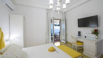 Une chambre d’hôtel avec un lit, un bureau équipé d’un ordinateur, une télévision et un balcon avec vue.