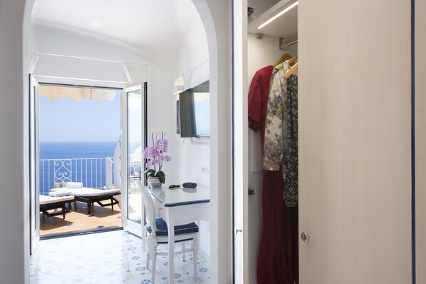 Een kamer met een balkon, een tafel met stoelen, een televisie en een spiegel.