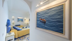 Una habitación de hotel con cama, escritorio, silla, un cuadro de un barco en el agua y suelo estampado.