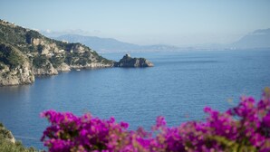 Un paisaje costero con un promontorio rocoso y una pequeña isla en la distancia.