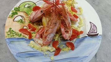 A plate with a seafood dish, including shrimp, on a decorative plate with a sailboat and sun design.