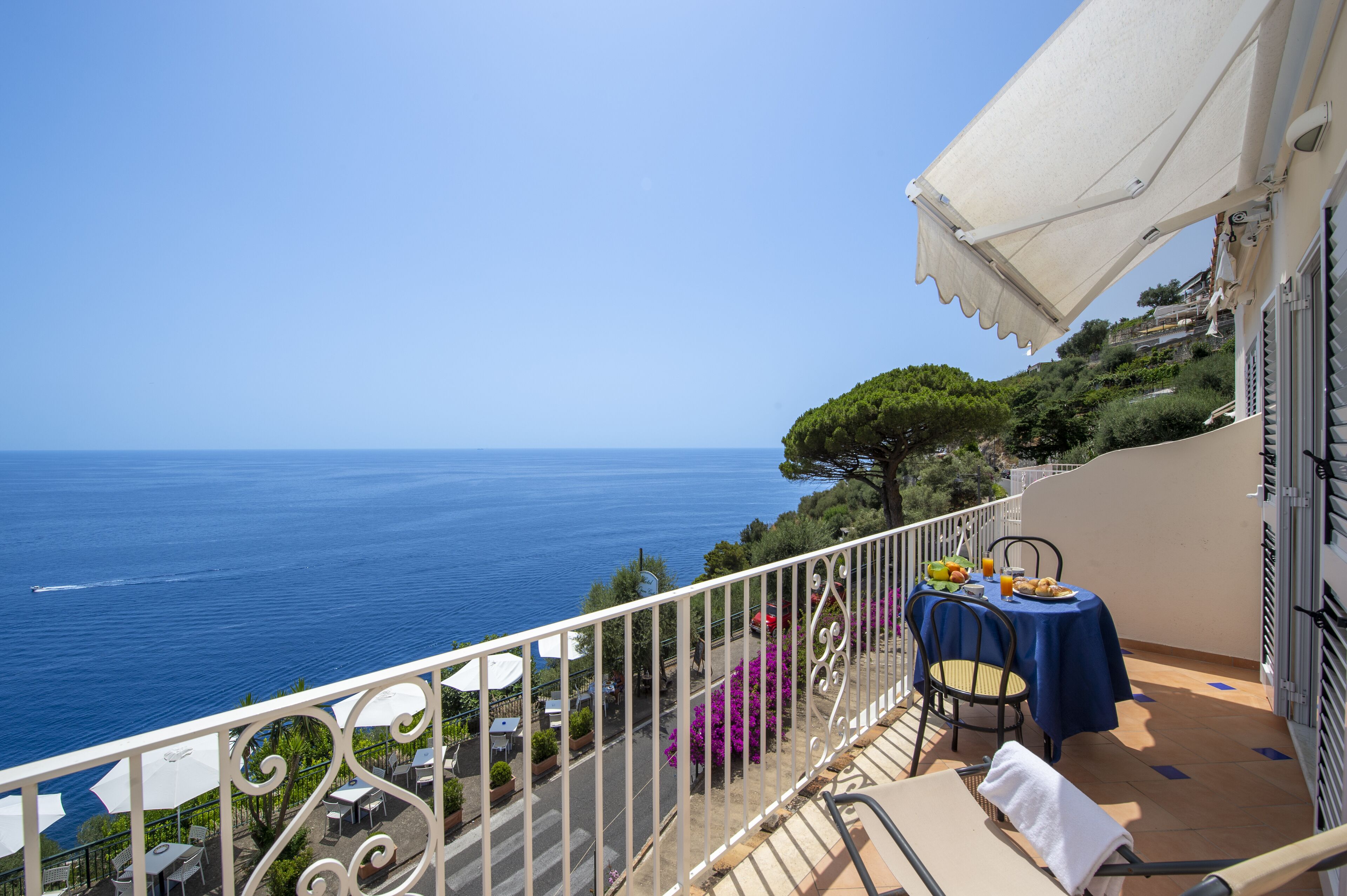 A balcony with a table set for two, overlooking the sea.