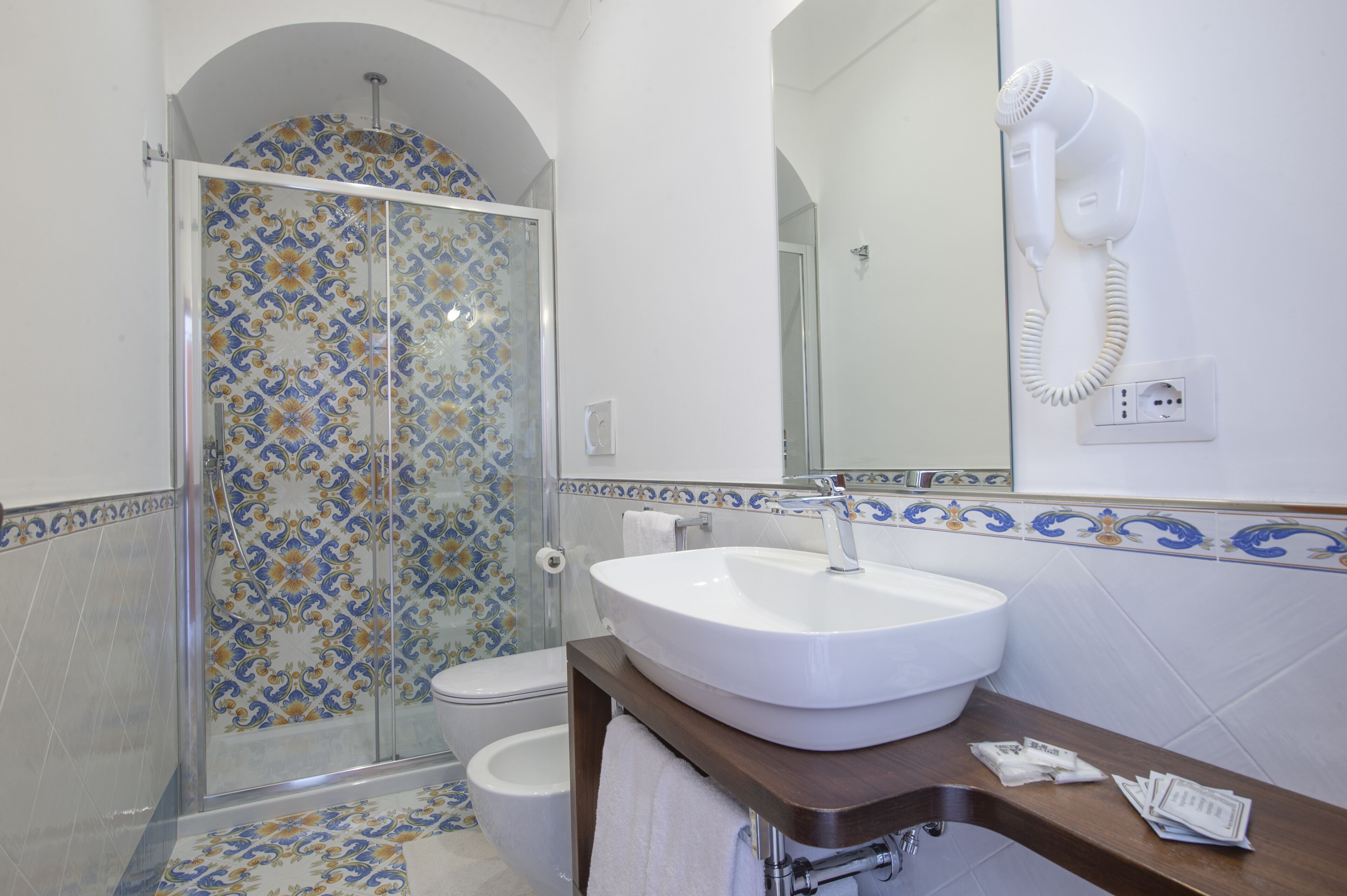 Een badkamer met een douche, toilet, wastafel en een haardroger bevestigd aan de muur.