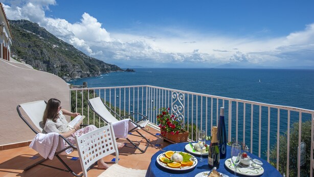 Un balcón con una mesa preparada para dos personas, con vista al mar.