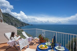 Een balkon met een tafel voor twee personen, met uitzicht op de kust.