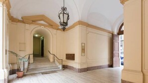 A spacious interior with a marble floor, a staircase, and a chandelier. - Marta Guest House (Rome)