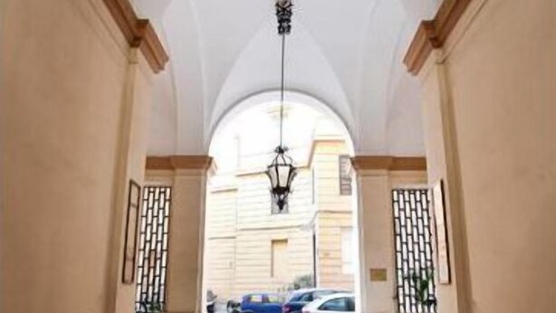 A hallway with a high ceiling and a hanging light fixture. - Marta Guest House (Rome)