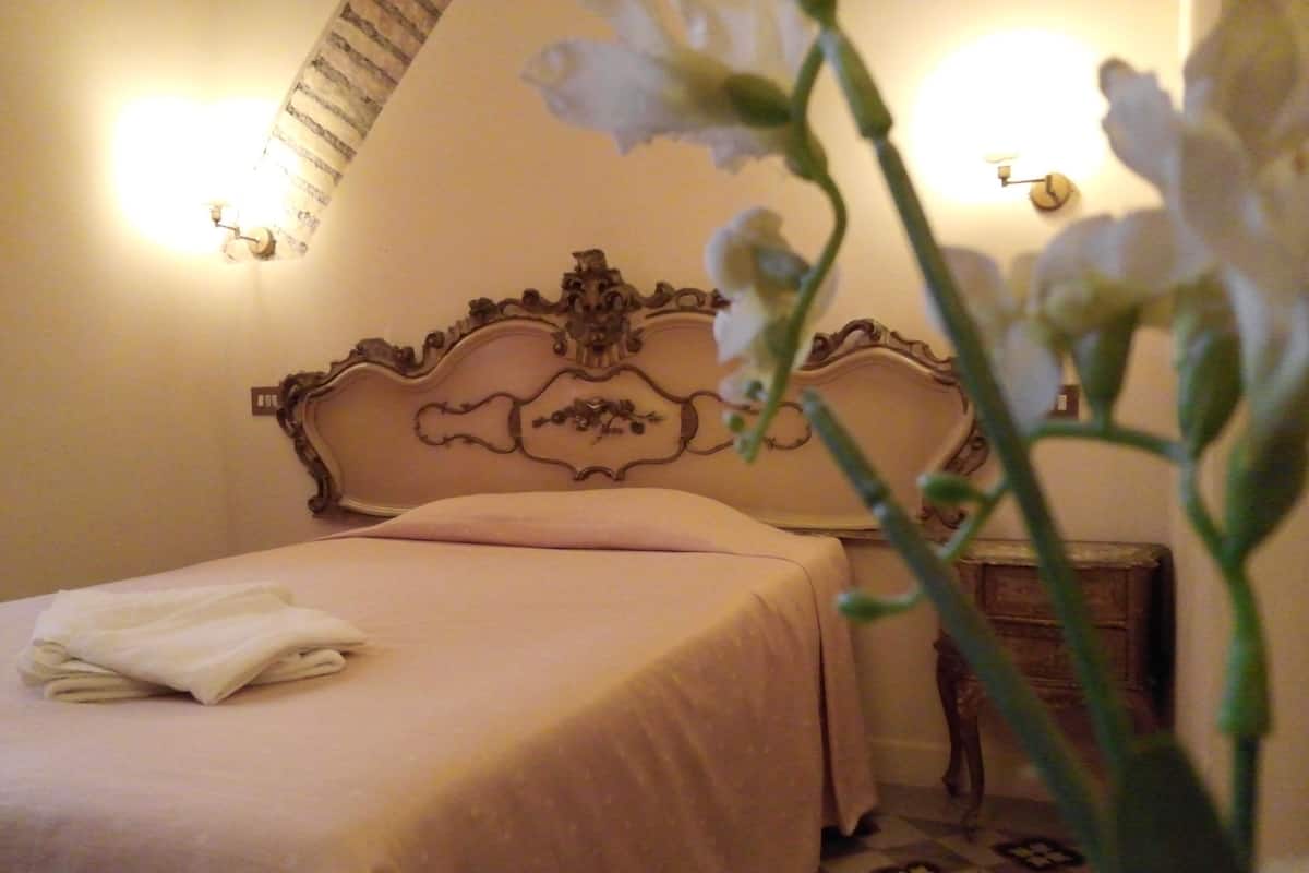 A neatly made bed with a headboard, a bedside table, and a wall-mounted light fixture.