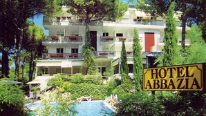 Un hôtel doté d’une piscine, entouré de verdure et agrémenté de nombreux balcons ornés de jardinières fleuries.