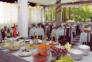 A dining area with tables set for a meal, featuring a variety of food items and beverages. - Hotel Abbazia (Lignano Sabbiadoro)