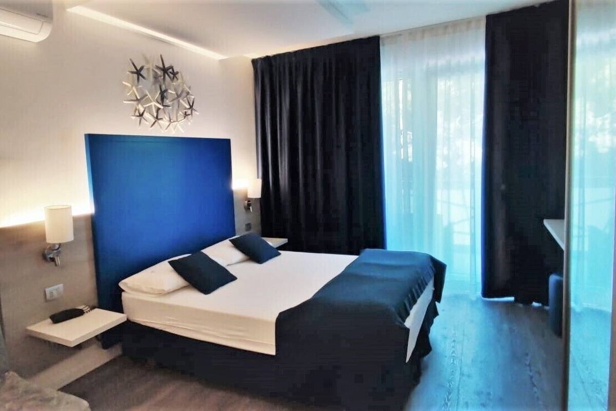 Une chambre d’hôtel avec un grand lit, une table de chevet, un bureau et une chaise.