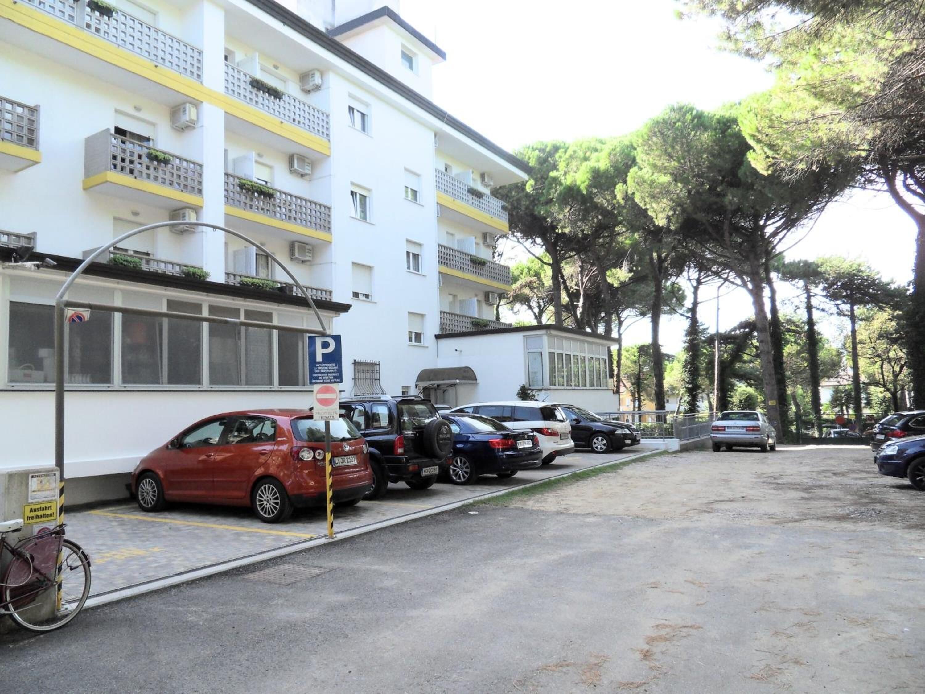 A parking lot with several cars, a bicycle, and a building with balconies.