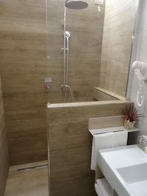 Een moderne badkamer met een douche, toilet en wastafel.