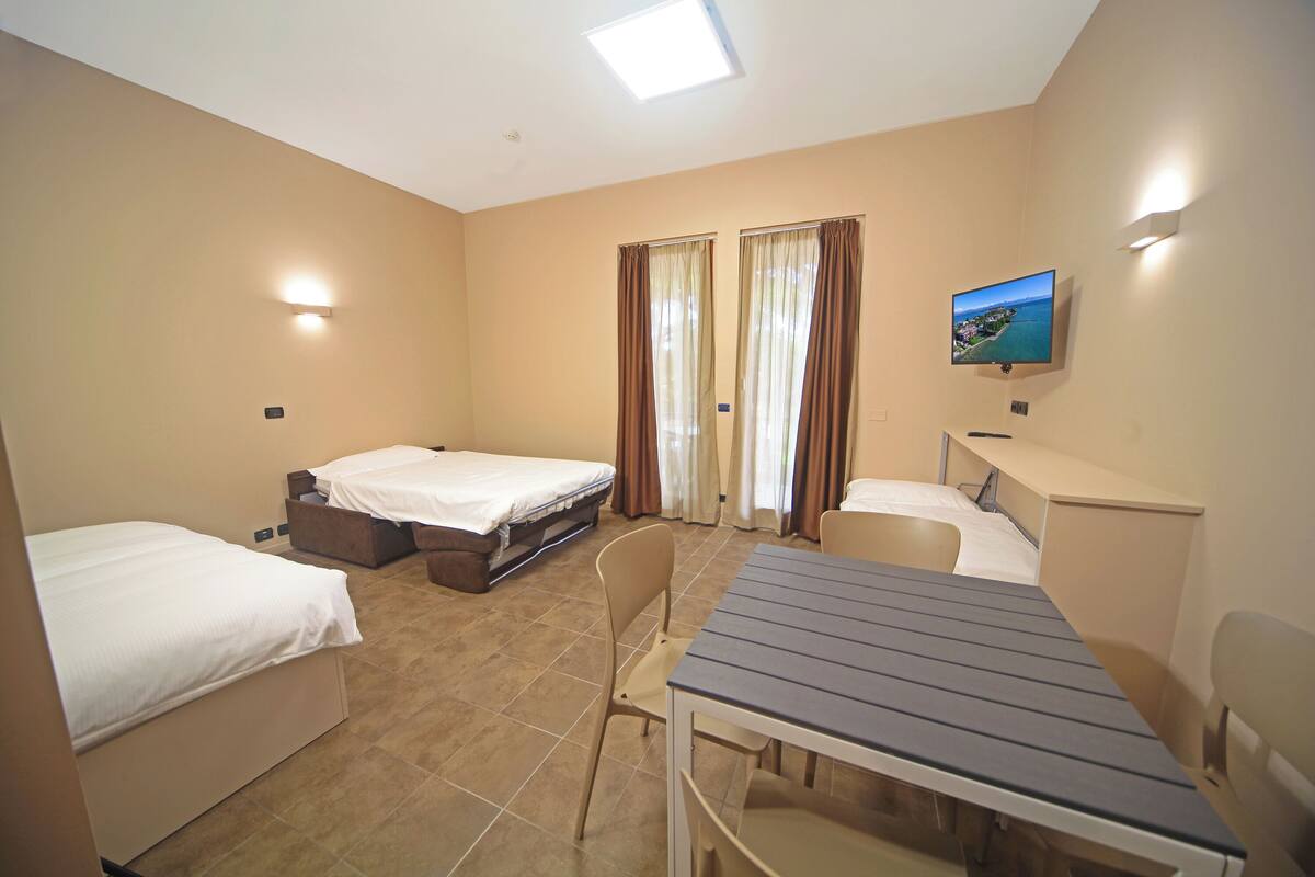 Een hotelkamer met twee eenpersoonsbedden, een bureau, een stoel, een televisie en een raam met gordijnen.