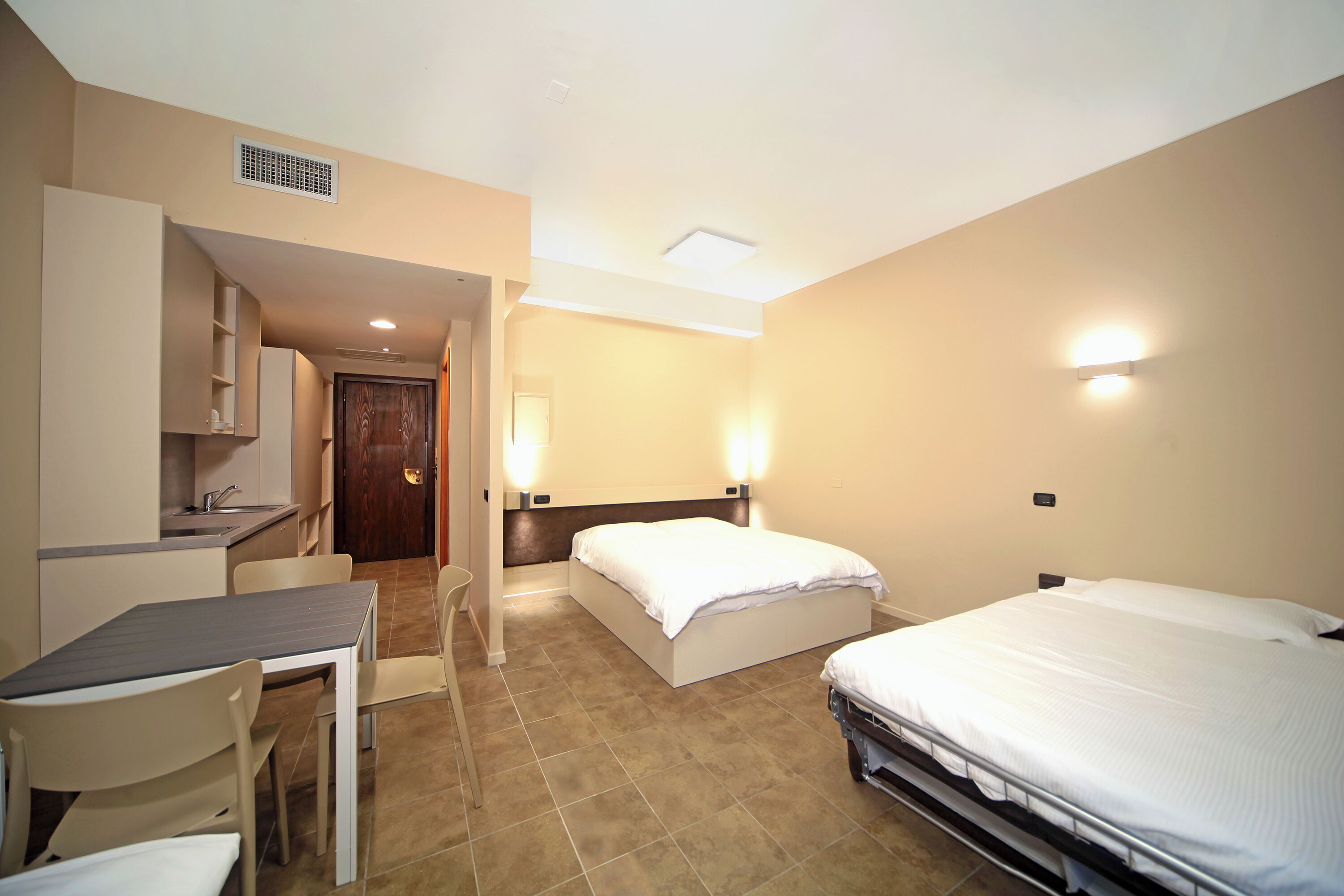 Quarto de hotel com cama, escrivaninha e cadeira.