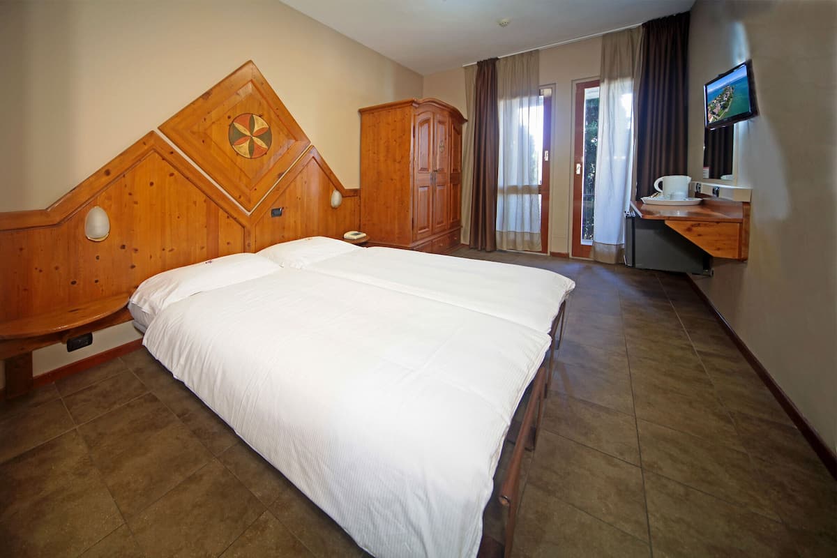 Een hotelkamer met een groot bed, een houten hoofdbord, een bureau met een televisie en een kledingkast.
