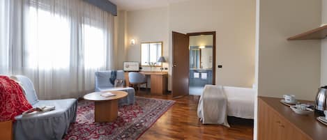 Una habitación de hotel con sofá, una silla, un escritorio, una cama y una mesita.