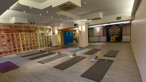 Un studio de yoga avec des tapis disposés sur le sol, une bibliothèque et une tapisserie décorative.