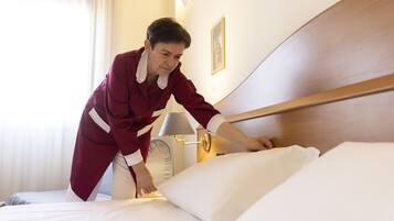Una camera d'albergo con un letto rifatto, una lampada da comodino e un quadro appeso al muro.