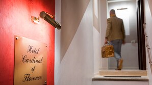 Placa de hotel com a inscrição 'Hotel Cardinal of Florence' e uma pessoa descendo uma escadaria.