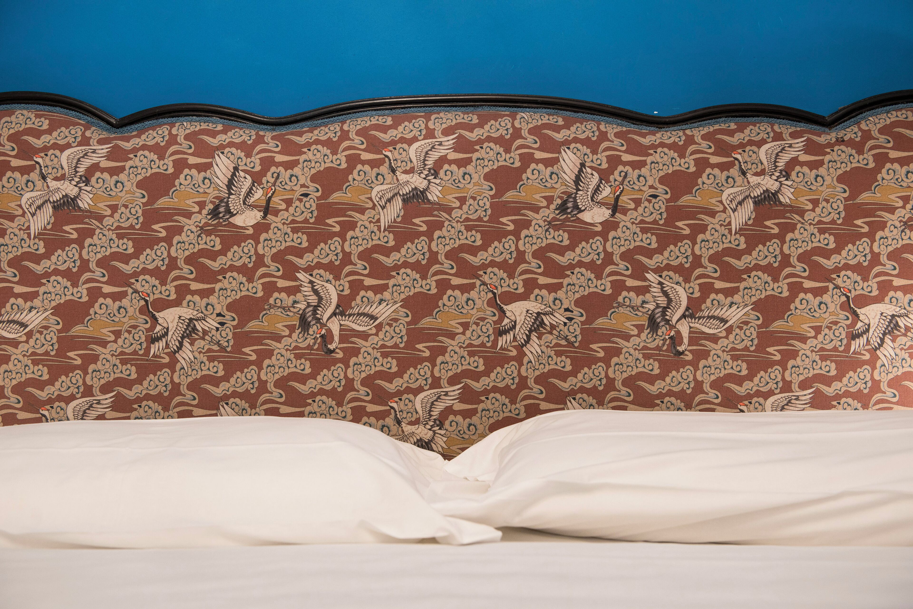 A bed with white linens and a headboard with a patterned design.