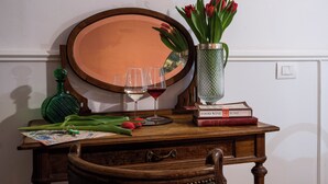 Un escritorio de madera con un espejo, dos copas de vino, un jarrón con tulipanes rojos, una botella verde y un libro titulado 'Food Wine Rome'.