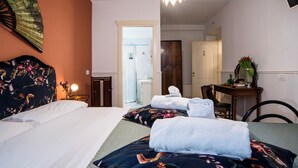 Habitación de hotel con cama, escritorio, silla, espejo y baño a la vista a través de una puerta abierta.