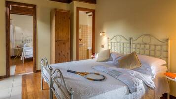 A bedroom with a bed, a wooden wardrobe, and a bathroom visible through an open door.