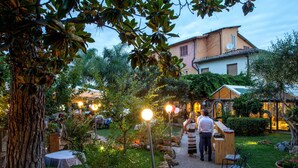 Un jardín exterior con barra de madera, mesas y sillas.