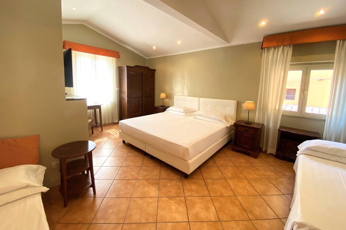 A spacious bedroom with a large bed, a desk, and a wardrobe.