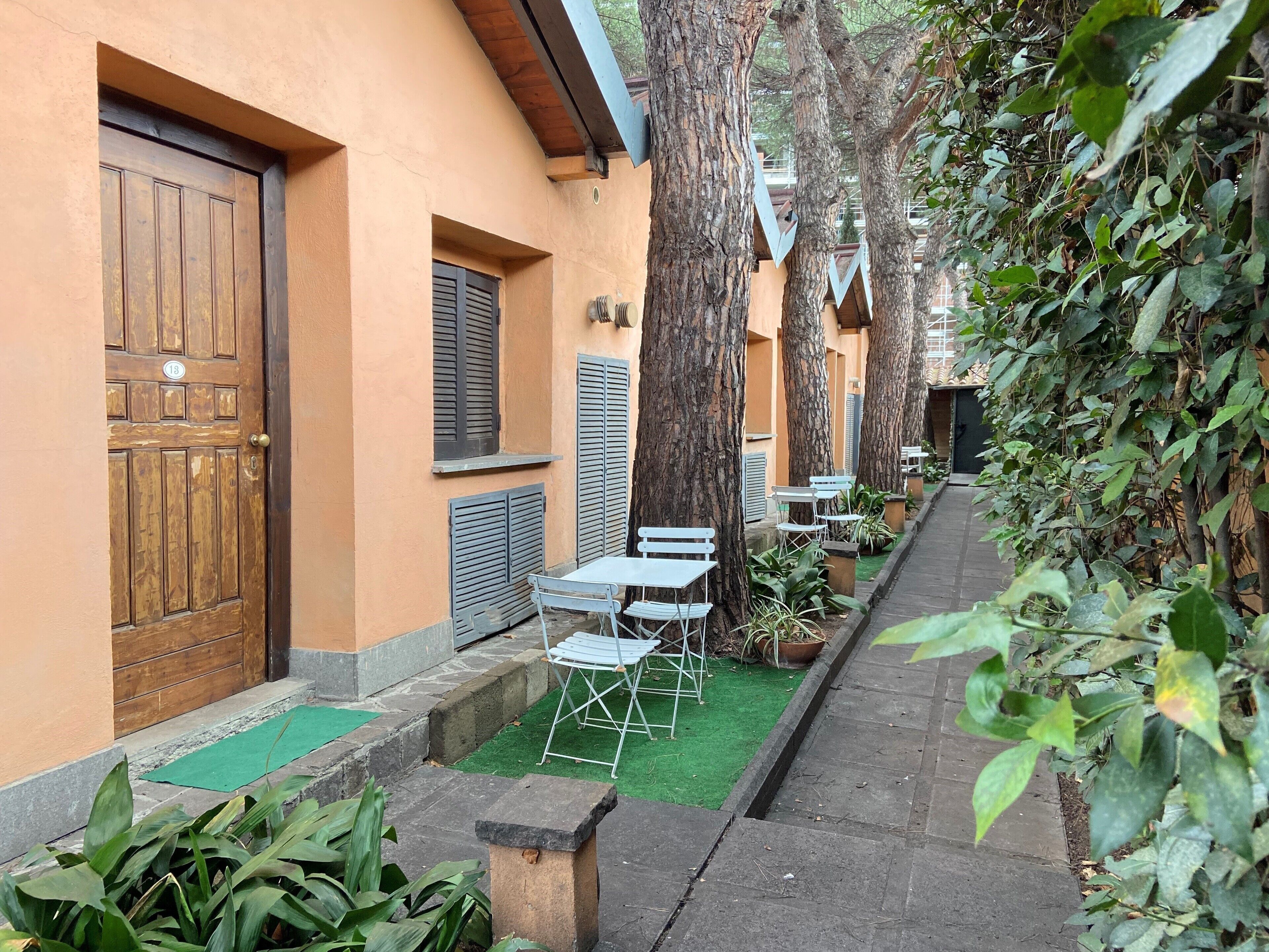 A courtyard with a wooden door, shuttered windows, and outdoor seating.