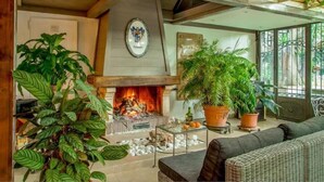 Una sala de estar acogedora con chimenea, plantas en macetas y un sofá de mimbre.