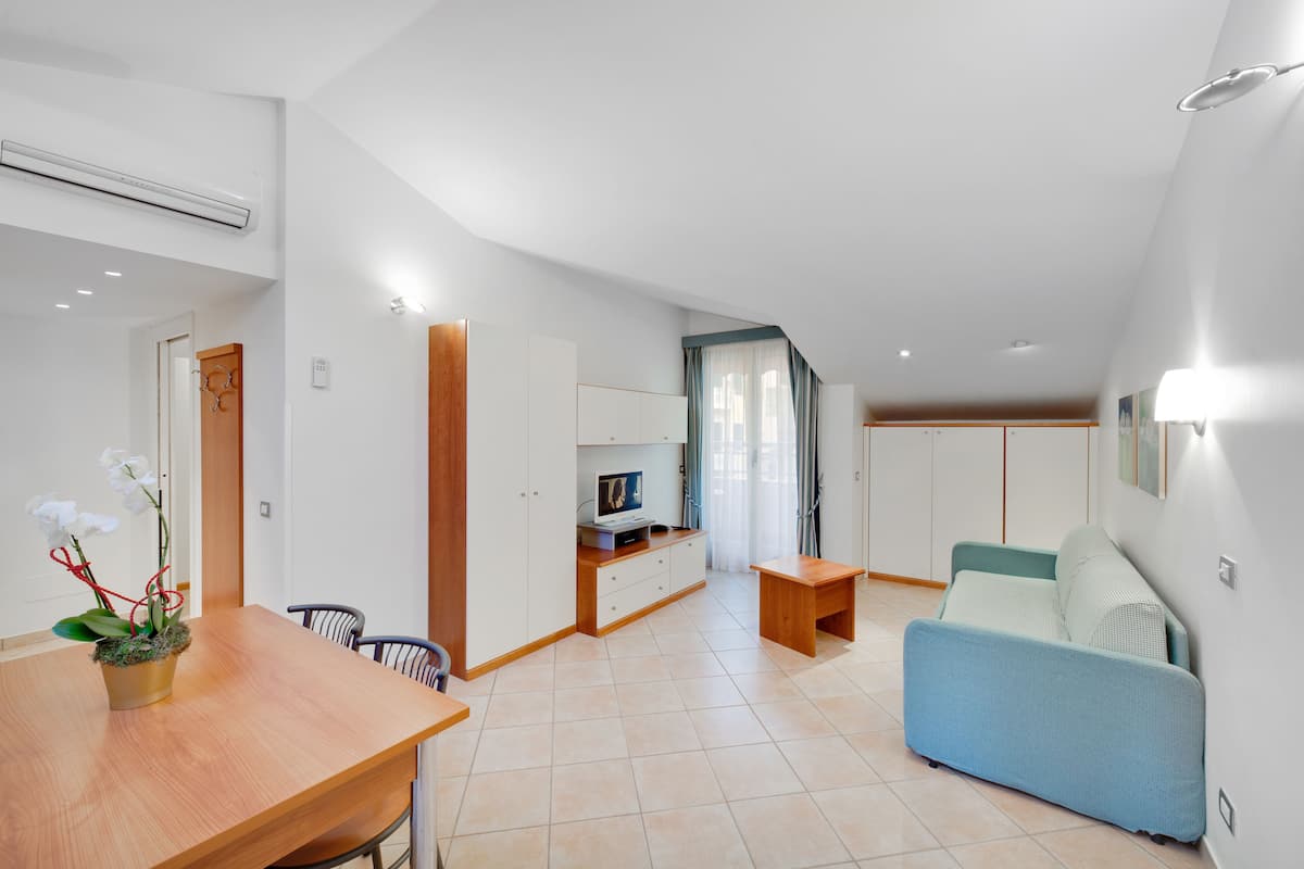 A modern apartment with a dining area, a sofa, a TV, and a small table.