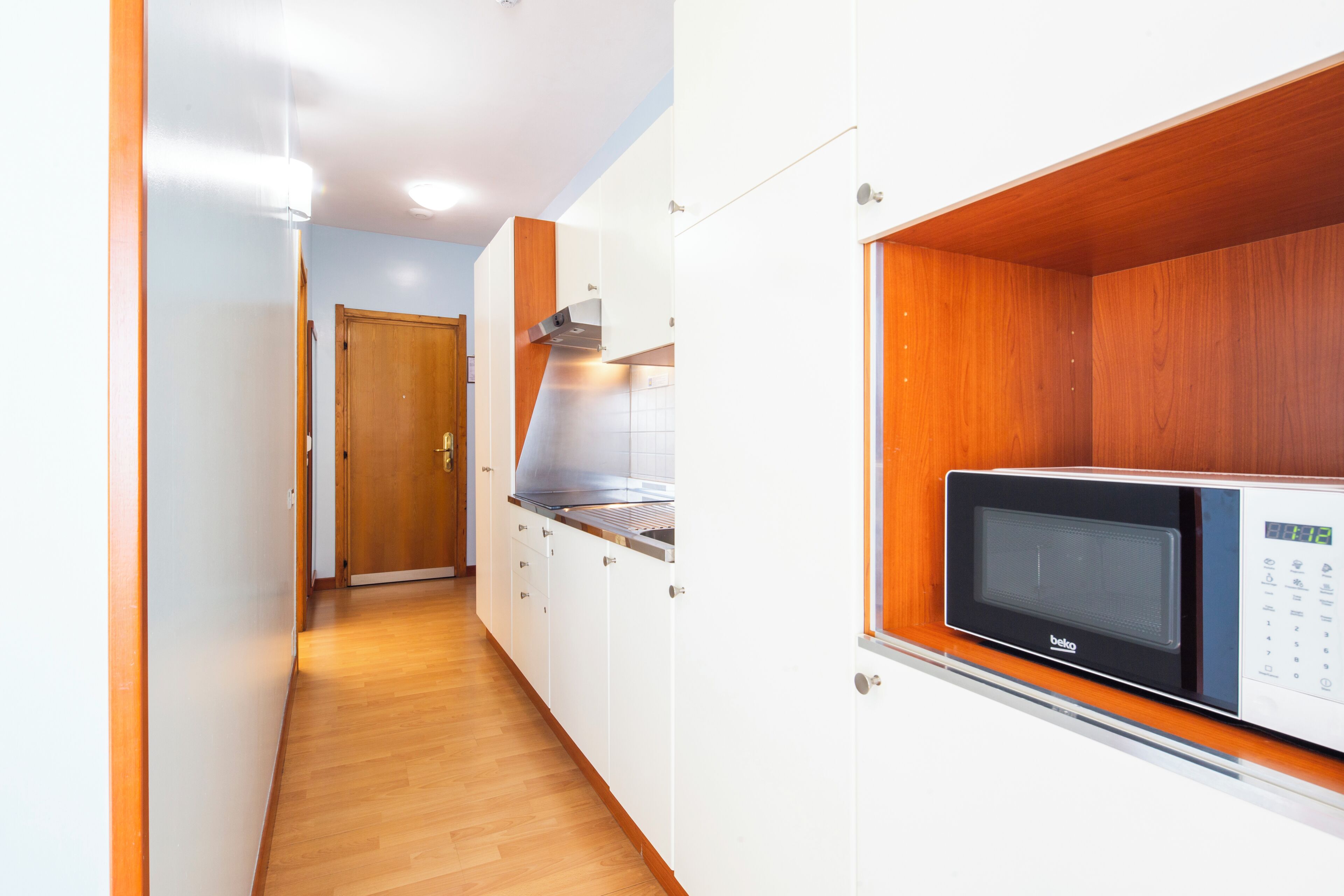 Una cucina con mobili bianchi, un piano di lavoro in legno e un forno a microonde integrato.