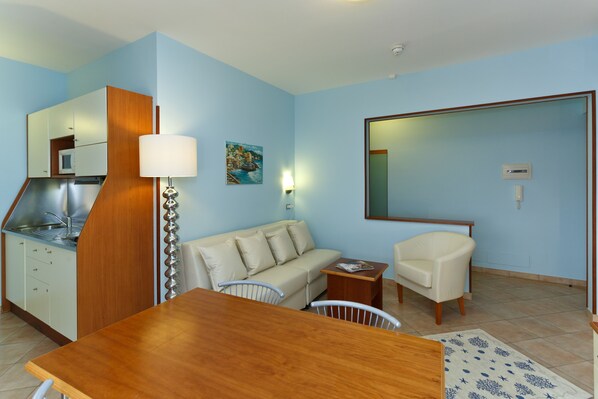 Un espacio habitable compacto con kitchenette, una mesa de comedor, un sofá y una silla.