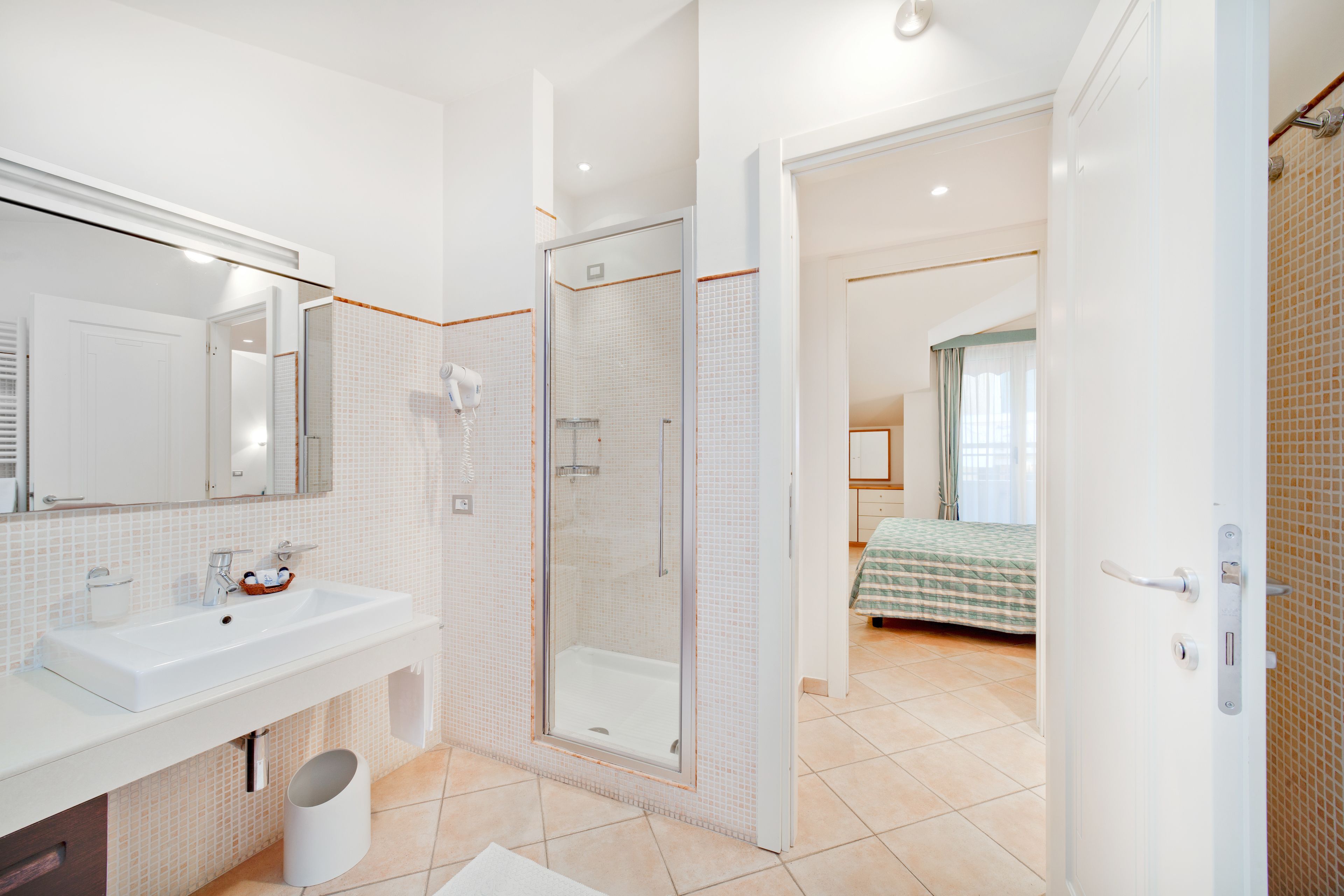 Un baño moderno con un espejo grande, lavamanos y ducha.
