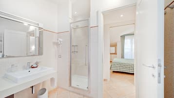 Un baño moderno con un espejo grande, lavamanos y ducha.