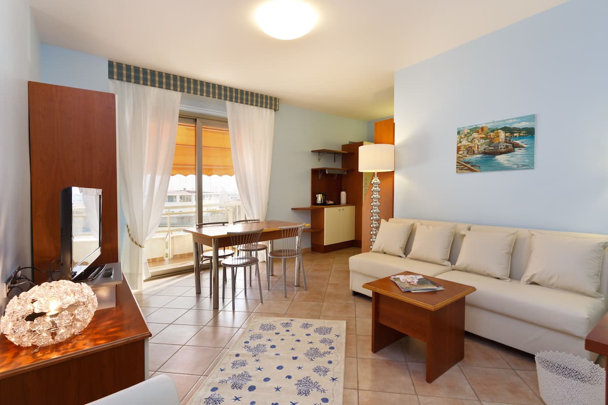 A living room with a sofa, coffee table, and dining area with chairs.