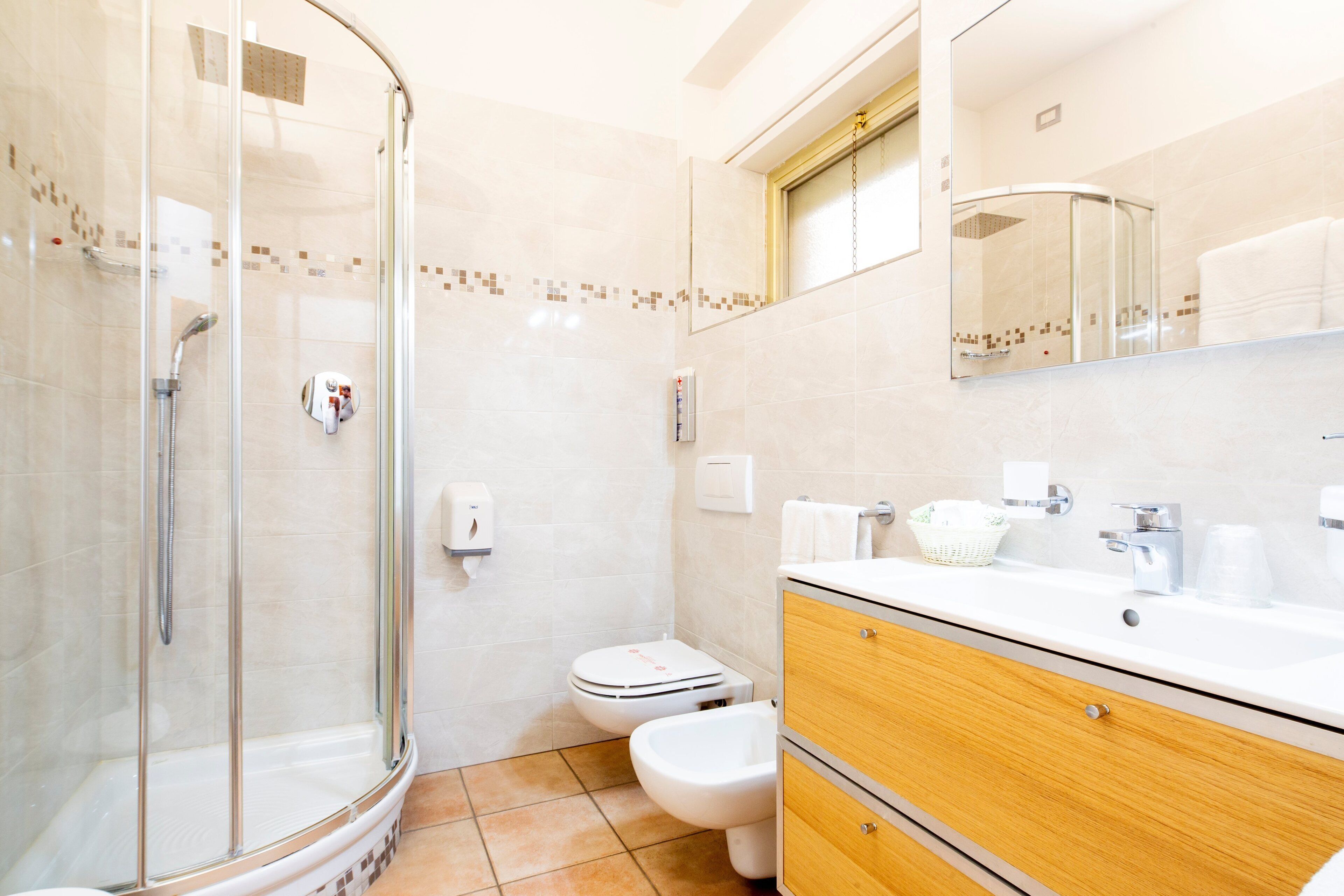 A bathroom with a glass-enclosed shower, a toilet, and a vanity with a mirror.