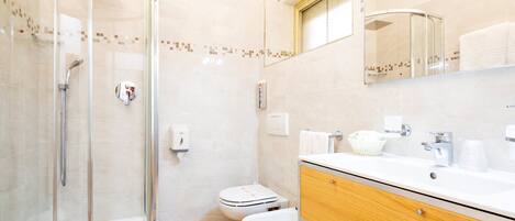A bathroom with a glass-enclosed shower, a toilet, and a vanity with a mirror.
