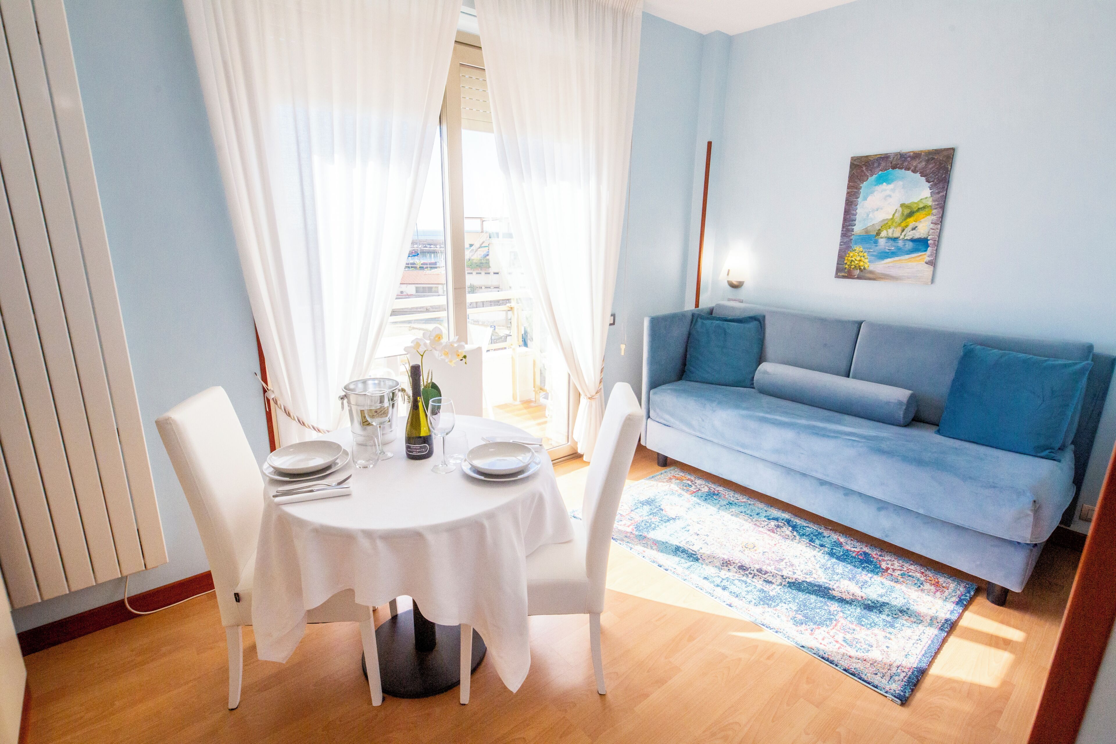 Ein Essbereich mit einem runden Tisch, weißen Stühlen und einem blauen Sofa.