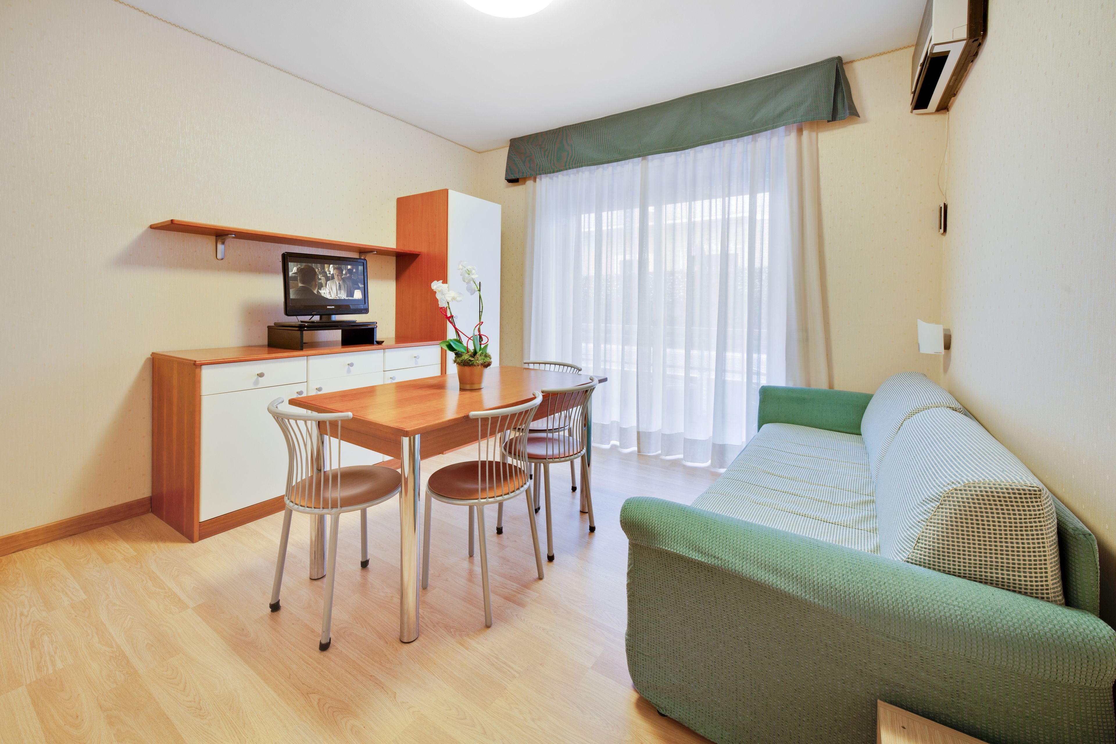 Un espacio habitable compacto con comedor, sofá y televisión.