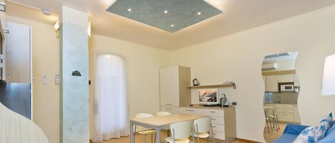 A compact living space with a dining area, kitchenette, and a sofa with a patterned cushion.