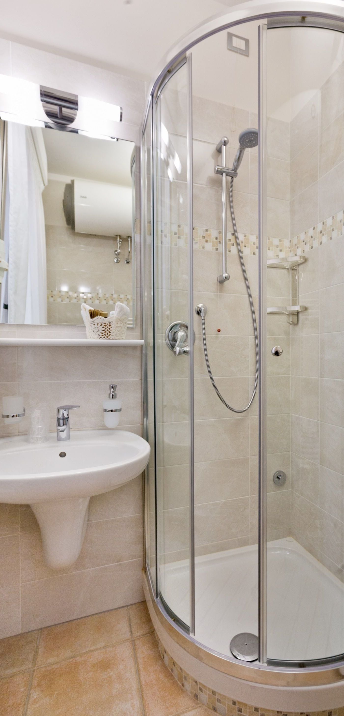 A modern bathroom with a glass-enclosed shower, a white sink, and a mirror above it.